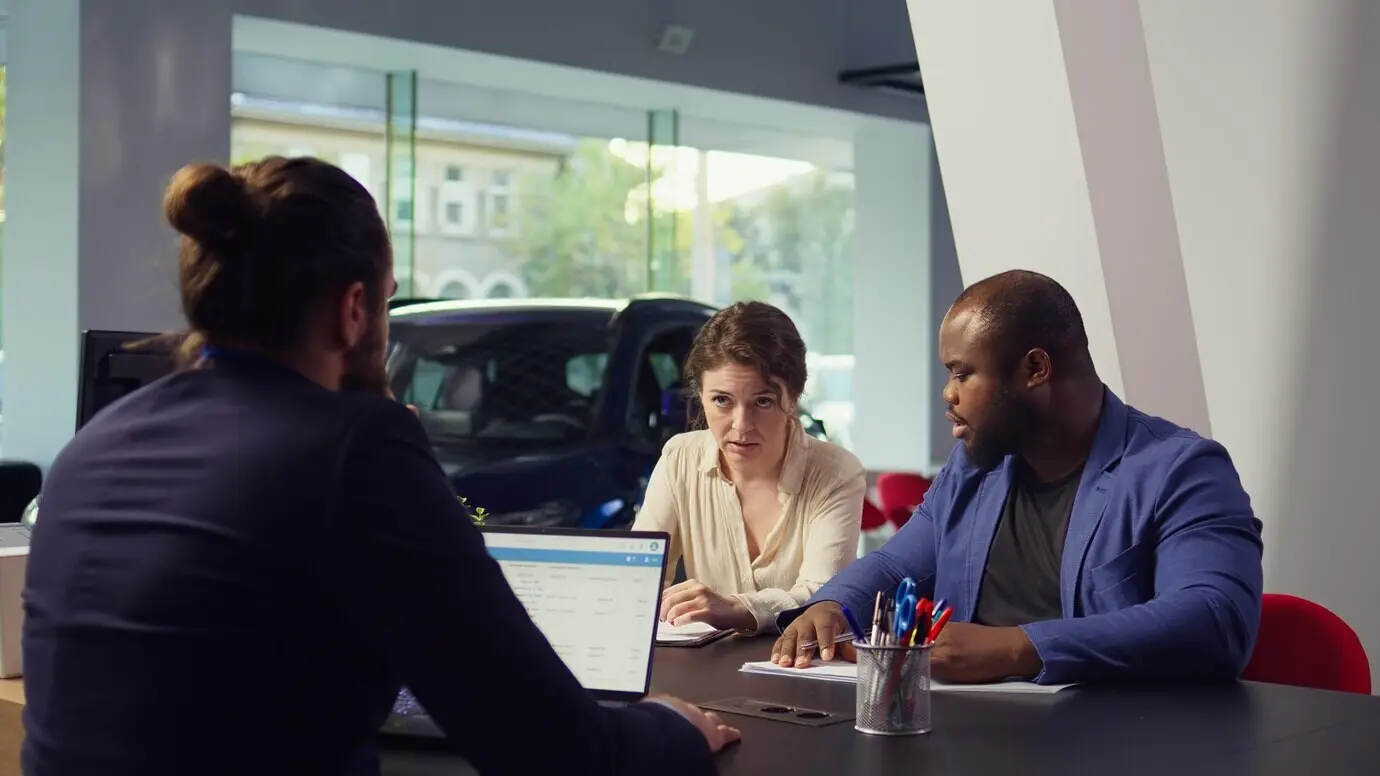 Customers at a dealership completing required car payment paperwork