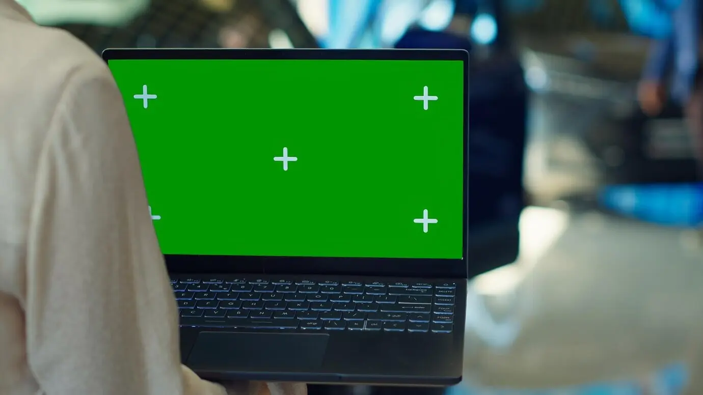 A customer in a showroom using a mockup laptop while looking for a new vehicle to purchase.